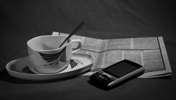 Kaffekop med en avis og en mobiltelefon